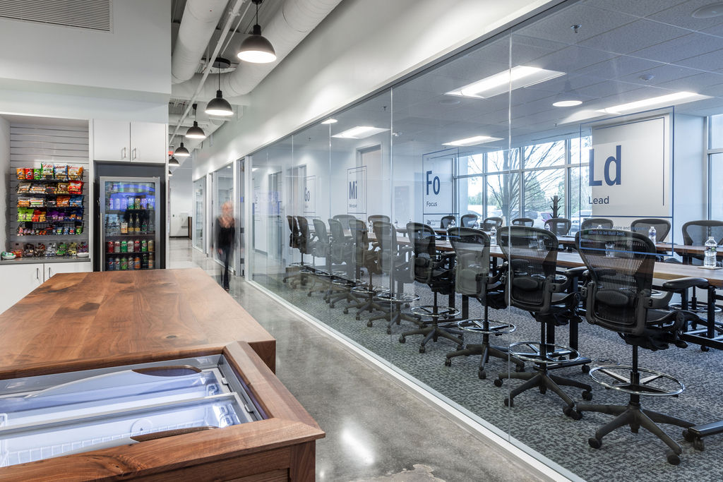 A person walking down the hallway at Transcend Leadership center with large meeting rooms and a snack bar on their right